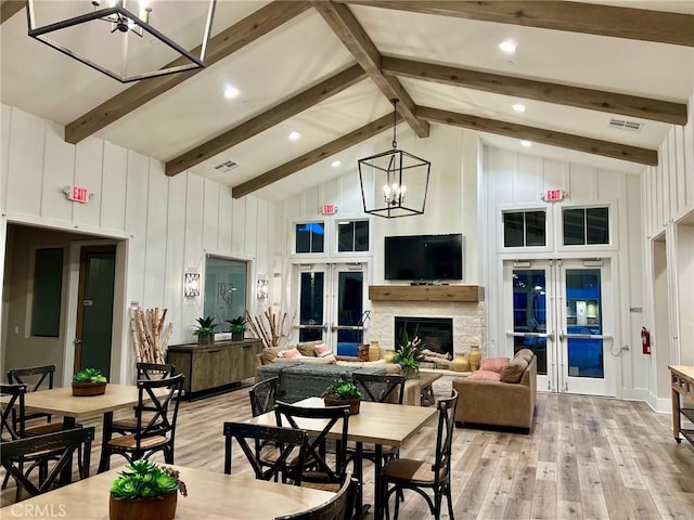 dining space with an inviting chandelier, french doors, light wood-type flooring, and high vaulted ceiling