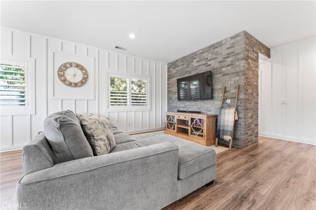 living area with a decorative wall, wood finished floors, and visible vents