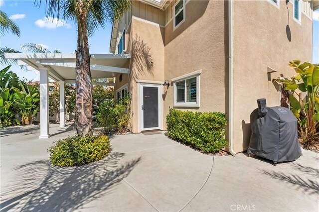 view of exterior entry featuring stucco siding and a patio