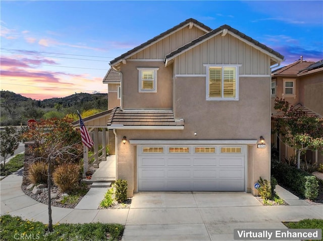 view of front of house with concrete driveway, a tiled roof, a garage, and stucco siding