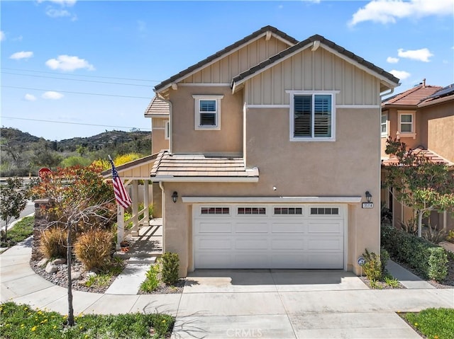 view of front of home featuring a tile roof, board and batten siding, driveway, and stucco siding