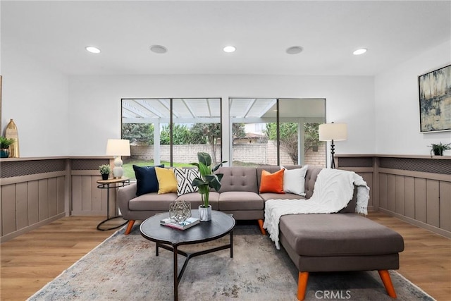 living area with recessed lighting, light wood-style floors, and a wainscoted wall