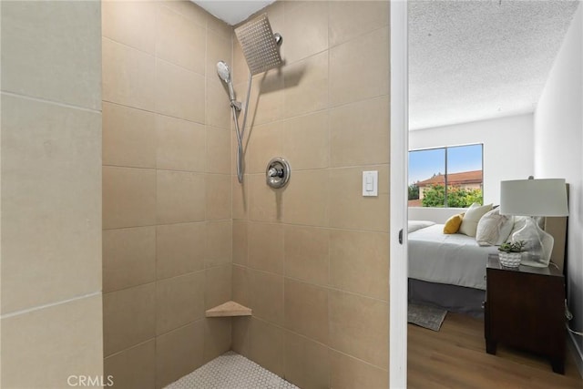 full bath with tiled shower, a textured ceiling, ensuite bath, and wood finished floors