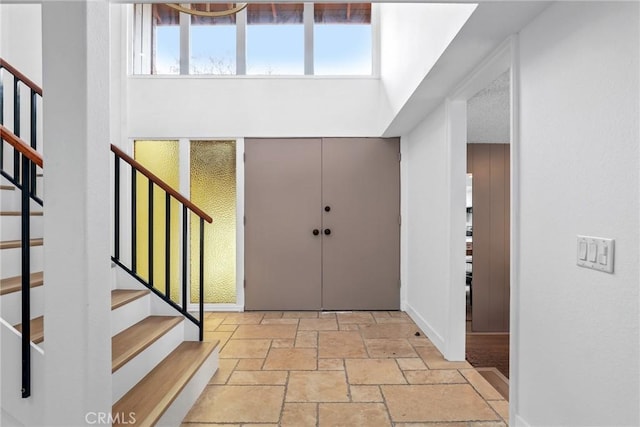 entryway featuring baseboards, stairway, and stone tile flooring
