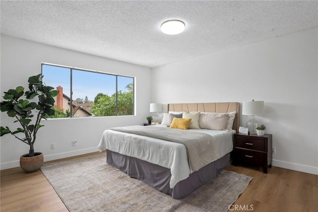 bedroom featuring wood finished floors, baseboards, and a textured ceiling