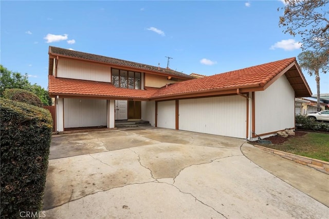 view of front facade featuring a tiled roof, an attached garage, and driveway