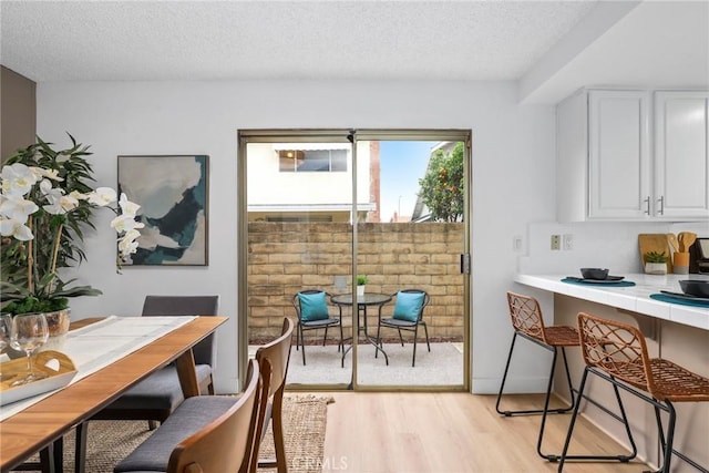 dining room featuring light wood-style floors and a textured ceiling