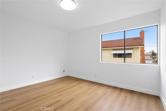 spare room with baseboards and wood finished floors