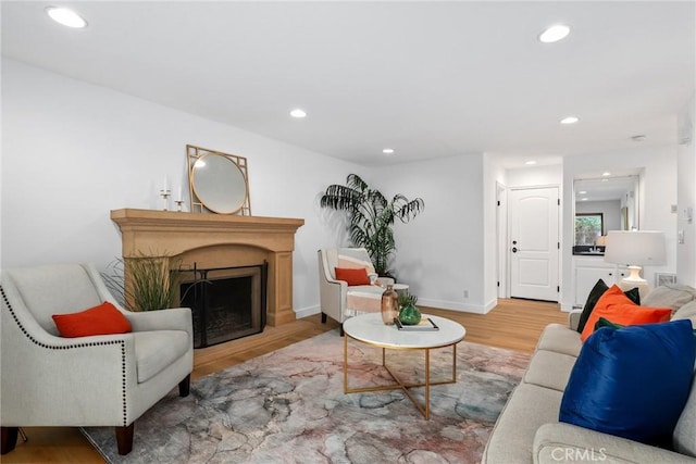 living room featuring recessed lighting, a fireplace, baseboards, and wood finished floors