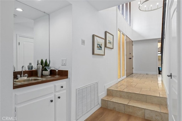 staircase featuring an inviting chandelier, wood finished floors, visible vents, and baseboards