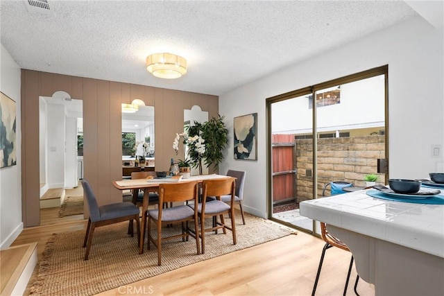 dining space featuring visible vents, light wood-style floors, and a textured ceiling