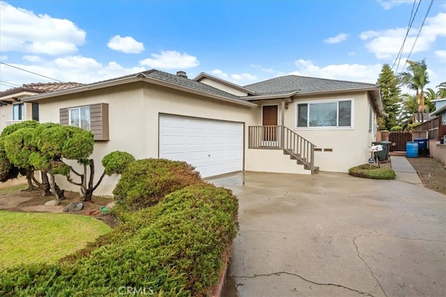 view of front of property with stucco siding, driveway, a garage, and fence