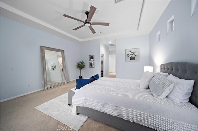 bedroom featuring a tray ceiling, light carpet, baseboards, and ceiling fan