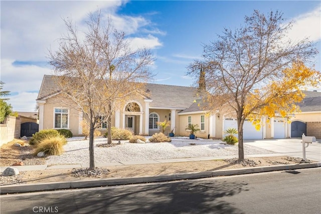 view of front facade with fence, a garage, driveway, and stucco siding