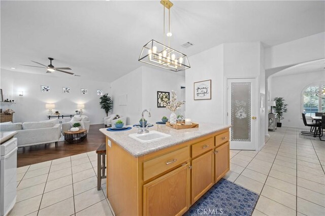 kitchen featuring a sink, open floor plan, arched walkways, white dishwasher, and light tile patterned floors