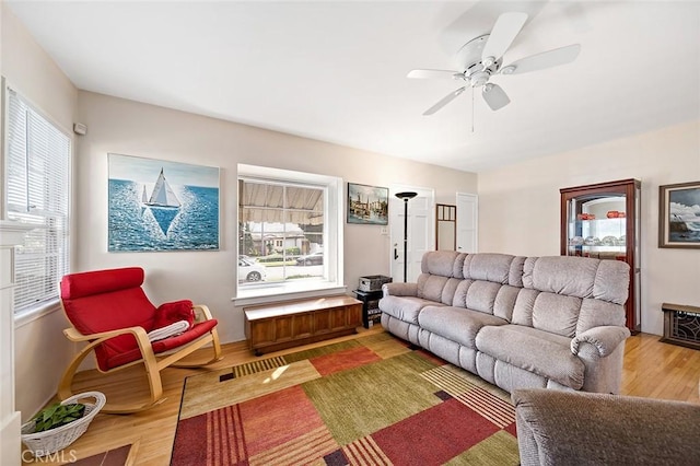 living room featuring light wood-style flooring, a ceiling fan, and a wealth of natural light