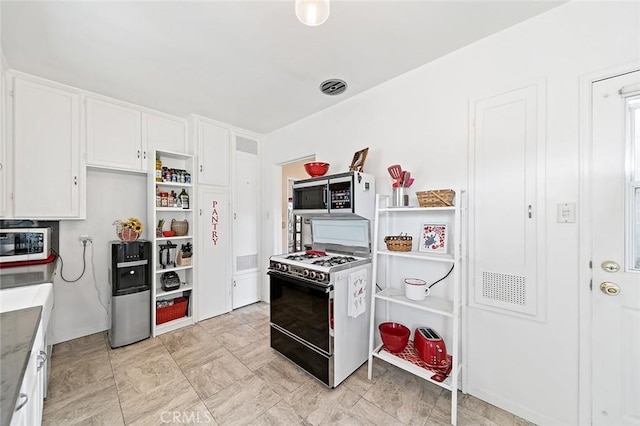 kitchen featuring range with gas stovetop, stainless steel microwave, visible vents, and white cabinetry