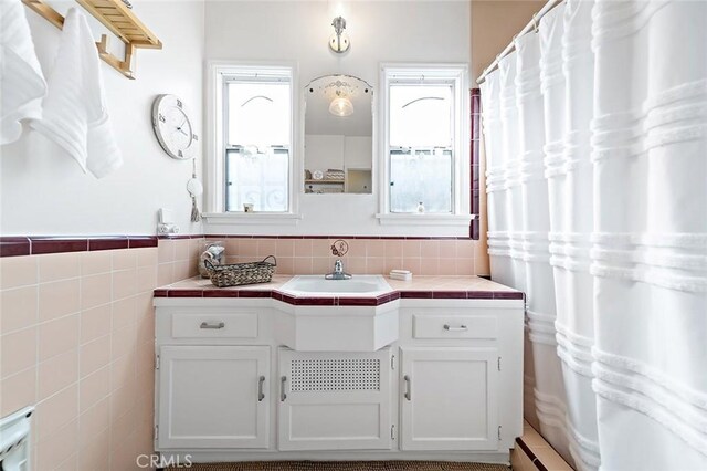 full bathroom with vanity, tile walls, and wainscoting