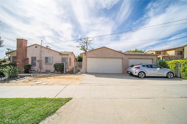 view of front of home with stucco siding, a detached garage, an outdoor structure, and fence