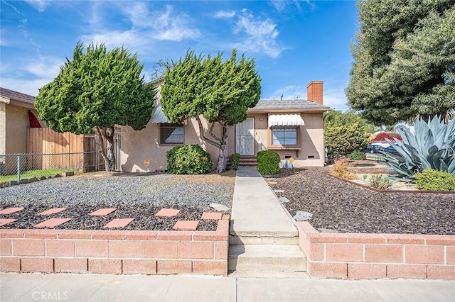 view of front facade featuring stucco siding, a chimney, and fence