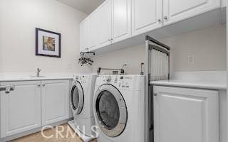 laundry area featuring washing machine and dryer, cabinet space, and a sink