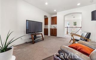 living room featuring arched walkways, recessed lighting, and light colored carpet