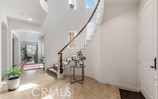 tiled foyer entrance featuring recessed lighting, arched walkways, and stairs