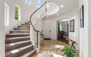 entryway with arched walkways, a healthy amount of sunlight, stairs, and a towering ceiling