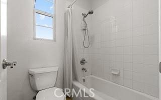 bathroom featuring toilet and shower / bath combo with shower curtain