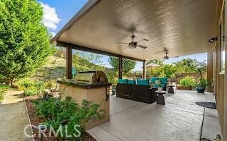 view of patio / terrace with an outdoor living space, a ceiling fan, and an outdoor kitchen