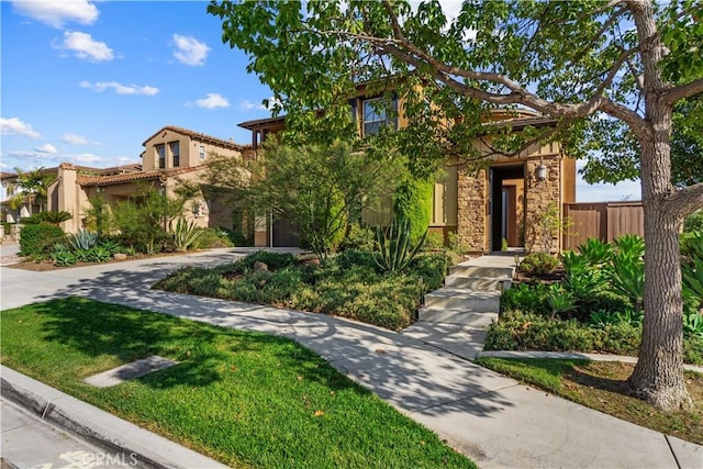 view of front facade featuring stucco siding, stone siding, and concrete driveway