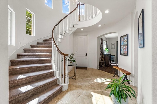 foyer with stairway, arched walkways, and a towering ceiling