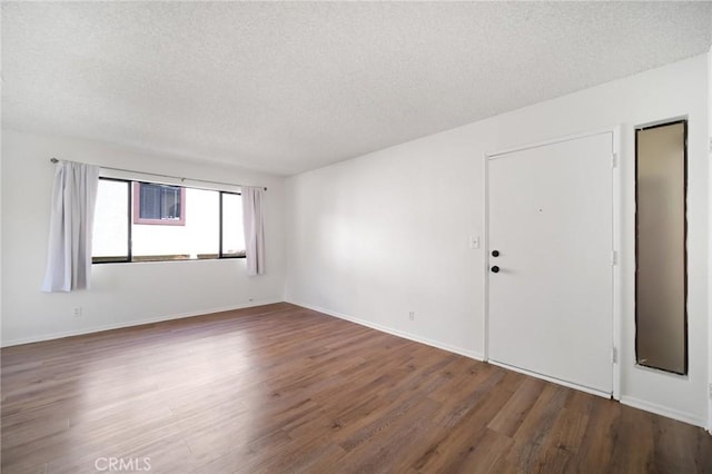 unfurnished room with wood finished floors, baseboards, and a textured ceiling