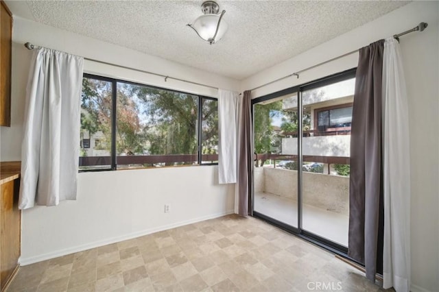 empty room featuring baseboards, a textured ceiling, and light floors