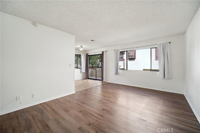 empty room with baseboards, a textured ceiling, and wood finished floors