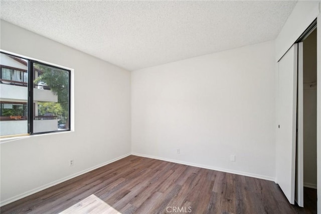 unfurnished bedroom with a closet, baseboards, a textured ceiling, and wood finished floors