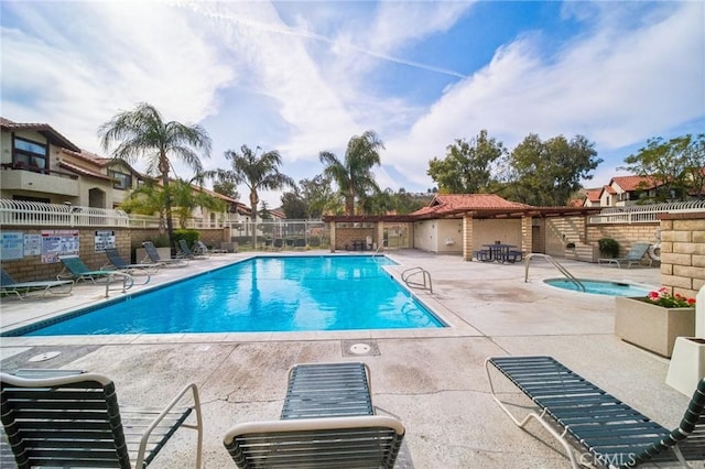 community pool featuring a patio area, a hot tub, and fence