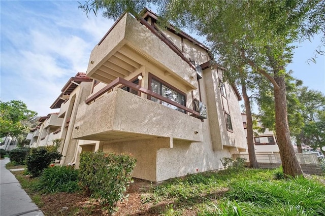 view of side of home featuring stucco siding and a balcony