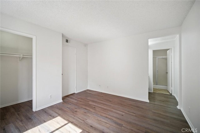 unfurnished bedroom featuring visible vents, a textured ceiling, wood finished floors, a closet, and baseboards