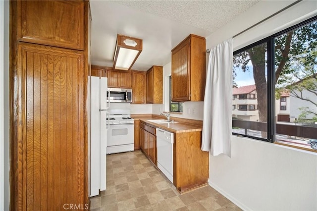 kitchen featuring a wealth of natural light, white appliances, light countertops, and a sink