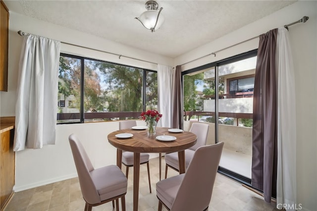 dining room featuring a textured ceiling and baseboards