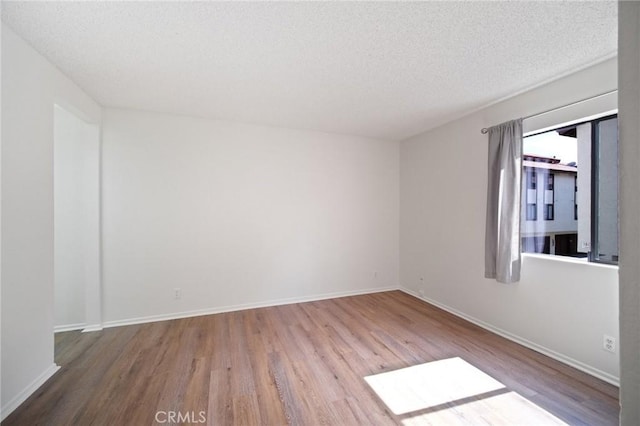 unfurnished room with wood finished floors, baseboards, and a textured ceiling