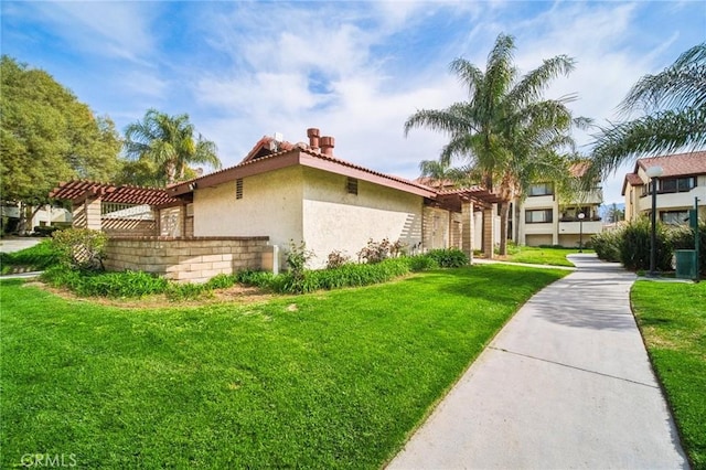 view of home's exterior featuring stucco siding, a pergola, and a yard