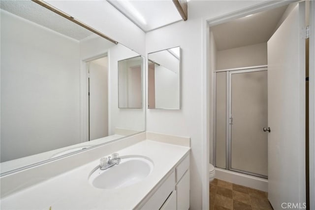 bathroom with toilet, a stall shower, and vanity