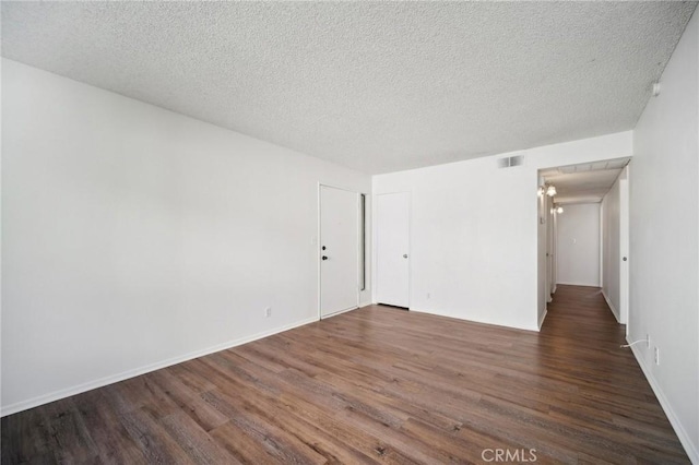 unfurnished room with visible vents, a textured ceiling, baseboards, and wood finished floors