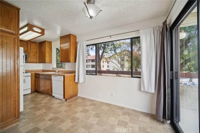 kitchen featuring brown cabinetry, stove, light countertops, a textured ceiling, and dishwasher