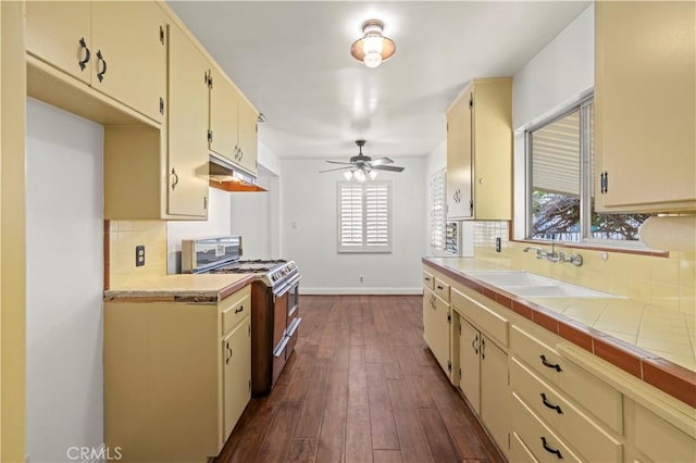 kitchen featuring a sink, double oven range, cream cabinets, and backsplash