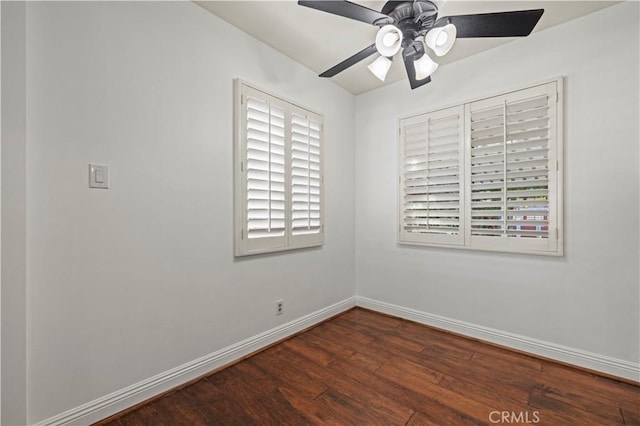 empty room featuring baseboards, dark wood-type flooring, and a ceiling fan