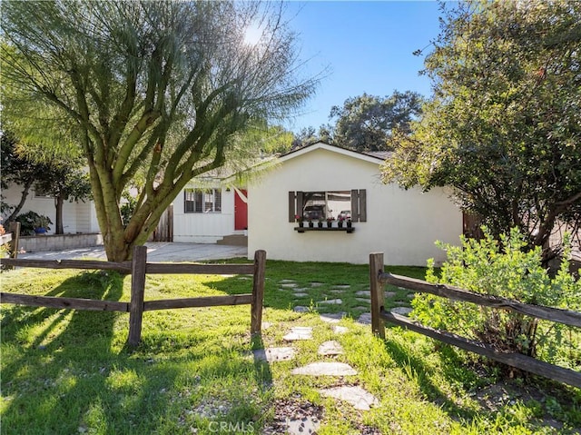 view of front facade with a front yard, fence, and stucco siding