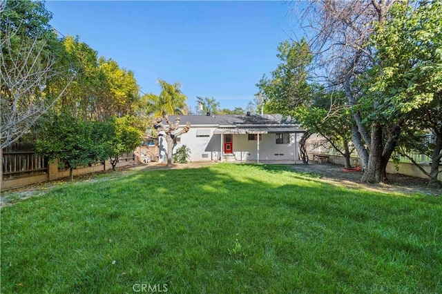 rear view of property featuring a fenced backyard, a patio, and a yard